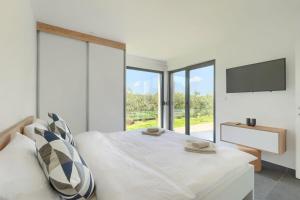 a white bedroom with a bed and a tv at Villa Vivre in Ližnjan +30 photos