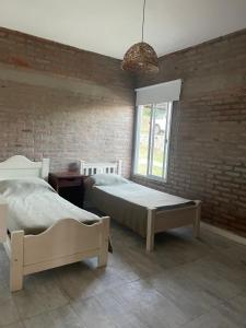 a bedroom with two beds and a brick wall at CHALET DE SIQUIMAN in Villa Parque Siquiman