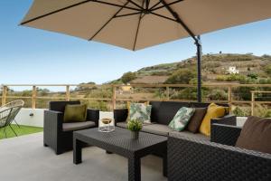a patio with a couch and a table and an umbrella at Villa con piscina y vista al mar in Moya