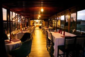 a restaurant with white tables and chairs and windows at Kaloni Hotels in Seeta