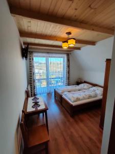 a bedroom with two beds and a table and a window at Willa WIDOKOWA CUDZICH in Zakopane
