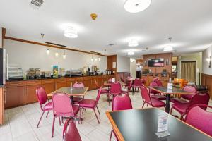 a restaurant with pink chairs and tables and a kitchen at Quality Inn & Suites Dawsonville in Dawsonville