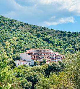 un bâtiment sur le côté d'une colline plantée d'arbres dans l'établissement SeaVista Sardinia, à Badesi