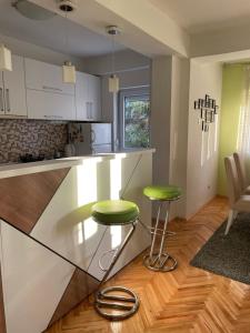 a kitchen with a counter and two green stools at Maria Charming Apartment in Kumanovo