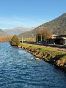 une rivière avec des rochers à côté d'une voie de train dans l'établissement Jacuzzi Suite Appartement bei Meran, à Merano