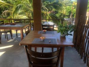 two wooden tables and chairs on a patio with palm trees at Painkiller Hiriketiya in Dickwella