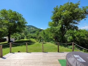 a wooden deck with a fence and trees and a field at Casuta dintre nuci in Blăjeni