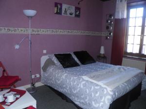 een slaapkamer met een groot bed met een paarse muur bij Le Moulin d'eclaron in Éclaron