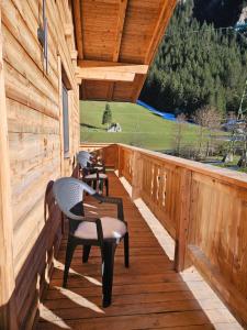 a wooden deck with chairs and a table on it at Alpenchalet Lengau in Dornauberg