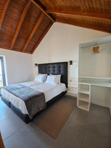 a bedroom with a large bed and a wooden ceiling at Quinta das Rosas 6 Amaizing Seaview Trekking Beach in Estreito da Calheta