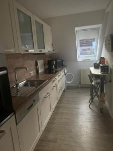 a kitchen with white cabinets and a sink and a table at Ostseebrise-Fehmarn in Fehmarn +28 photos