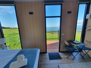 a bedroom with a bed and a desk and a balcony at Aorangi Peak Cabins 5 by Tiny Away in Rotorua