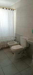 a white bathroom with a toilet and a sink at Departamento el estadio in Santiago del Estero