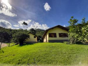 a small house on a grassy field next to a house at Refúgio da Colina Lumiar 3quartos 2banheiros 10pessoas in Nova Friburgo