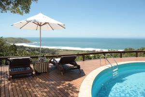 a swimming pool with two chairs and an umbrella at Bangalore Suites in Garopaba