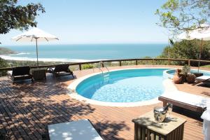 a swimming pool on a deck with a view of the ocean at Bangalore Suites in Garopaba
