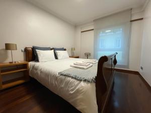 a bedroom with a bed with white sheets and a window at Apartamento Arrabida in Lisbon