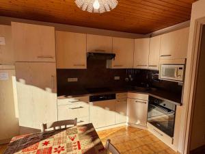 eine Küche mit weißen Schränken, einem Tisch und einer Mikrowelle in der Unterkunft Chalet charmant avec balcon sud et Multi Pass à 3€/jour! - FR-1-692-22 in La Chapelle-dʼAbondance
