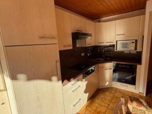 eine Küche mit weißen Schränken und einer Mikrowelle in der Unterkunft Chalet charmant avec balcon sud et Multi Pass à 3€/jour! - FR-1-692-22 in La Chapelle-dʼAbondance
