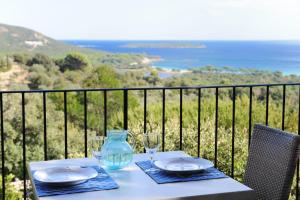 a table with plates and glasses on a balcony at Résidence Belvedere de Palombaggia in Porto-Vecchio