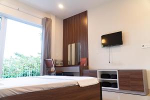a bedroom with a bed and a tv on a wall at Homestay 5 Sach in Hue