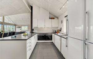 a kitchen with white cabinets and black counter tops at 7 Bedroom Nice Home In Hvide Sande in Nørre Lyngvig