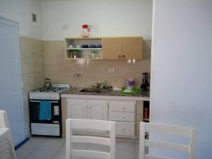 a kitchen with a stove and white cabinets and white chairs at Moana II in Las Grutas +10 photos