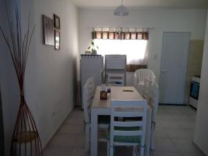 a kitchen with a white table and white chairs at Moana II in Las Grutas