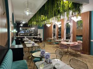 ein Restaurant mit Tischen, Stühlen und Pflanzen in der Unterkunft Alison Boulevard Hotel in Baku