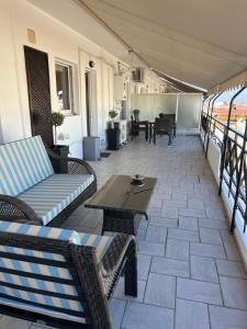eine Terrasse mit Sofas und Tischen auf einem Balkon in der Unterkunft 19 Αri in Tríkala