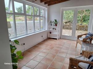 ein Wohnzimmer mit großen Fenstern und Fliesenboden in der Unterkunft The Stables in Aglish + 3 Fotos