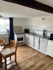 a kitchen with white cabinets and a table and chairs at Unterkunft Dähre in Dähre