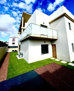 a white house with a balcony and green grass at Golf villa heated pool relax tenerife south in San Miguel de Abona