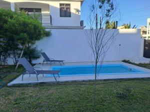a swimming pool with two chairs next to a house at Maison Mont Choisy - One or Two Bedrooms Apartment in Trou aux Biches