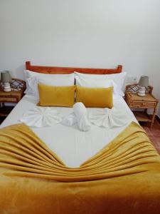 a large bed with white sheets and yellow pillows at Casa turística Lirio in Chandreja