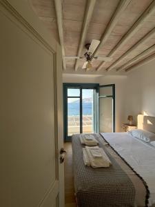 a bedroom with a bed with a ceiling fan and a window at Almyra Yellow Villa in Kithnos