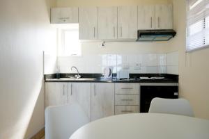 a kitchen with white cabinets and white chairs and a sink at Oceanic eleven in Durban