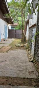 a walkway in front of a house with a tree at Casa aconchegante perto da praia in Guarujá