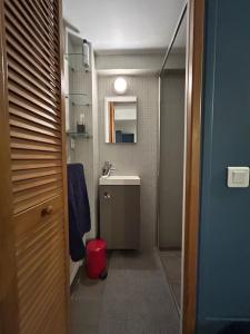 - une petite salle de bains pourvue d'un lavabo et d'une poubelle rouge dans l'établissement Villa Ribot, à Paris