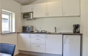a kitchen with white cabinets and a sink and a microwave at Holiday Home Halvejen Hytte Spjald Ii in Spjald