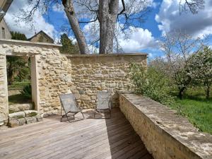 two chairs on a wooden deck with a stone wall at LE VERGER in Vaux-sur-Seine