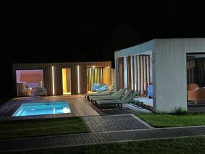a patio with chairs and a pool at night at Leśna Polana Domki in Okuninka