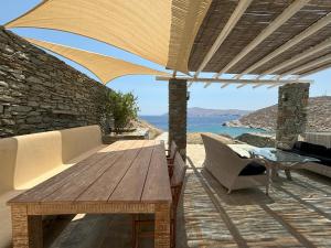 a patio with a wooden table and an umbrella at Almyra Red Villa in Kithnos