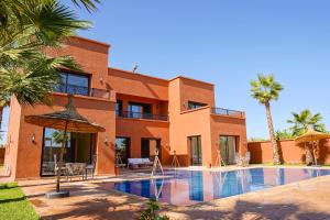 une maison avec une piscine et des palmiers dans l'établissement VILLA NOÛR PALACE avec piscine jaccuzi à Marrakech, à Marrakech