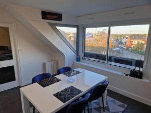 a dining room with two tables and two windows at Glaz - appart-sympa - T1 bis en plein centre de Plœmeur in Ploemeur