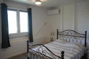 una camera da letto con un letto e due finestre di Carbet,bord de mer a Le Carbet