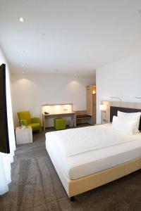 a bedroom with a large white bed and green chairs at Hotel Go2Bed Weil am Rhein - Basel in Weil am Rhein