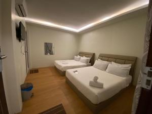 a bedroom with two beds with white sheets at LE dEON HOTEL Former Pine Hotel in Batu Gajah