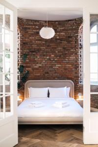 een slaapkamer met een wit bed en een bakstenen muur bij Apartament Studio Migot in Przemyśl
