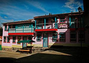 um edifício colorido com um banco à frente em Hotel Los Geranios em Duitama